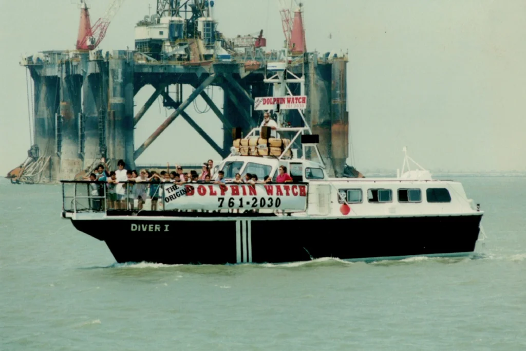 The M/V Diver I running an early Original Dolphin Watch trip past an offshore rig